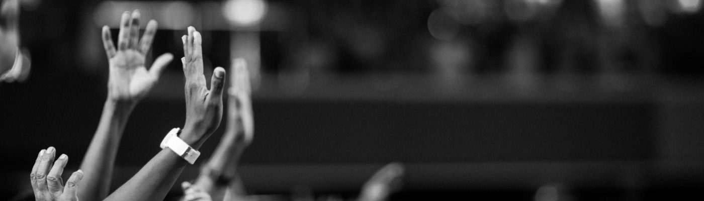 Black and white image of audience with hands raised, capturing concert energy.